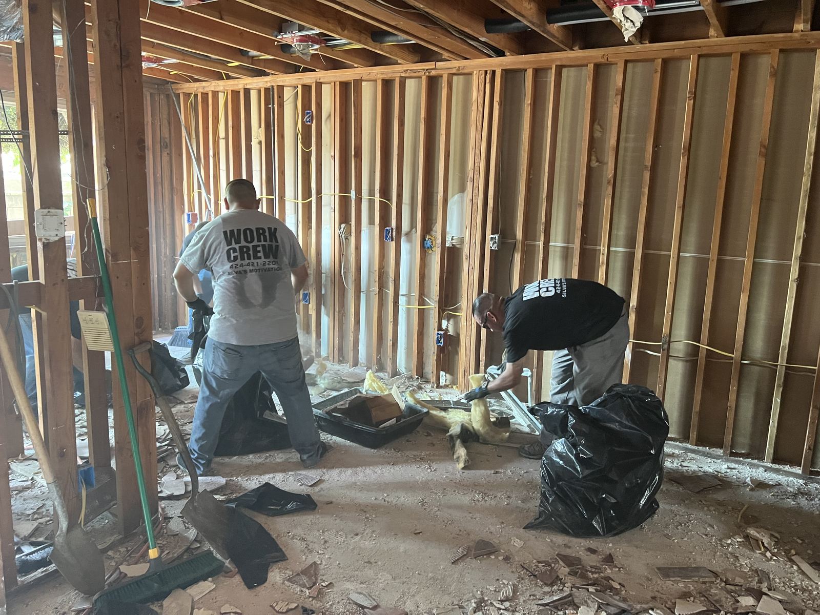 Silva's Motivation work crew members clearing debris and insulation during a home rehab project