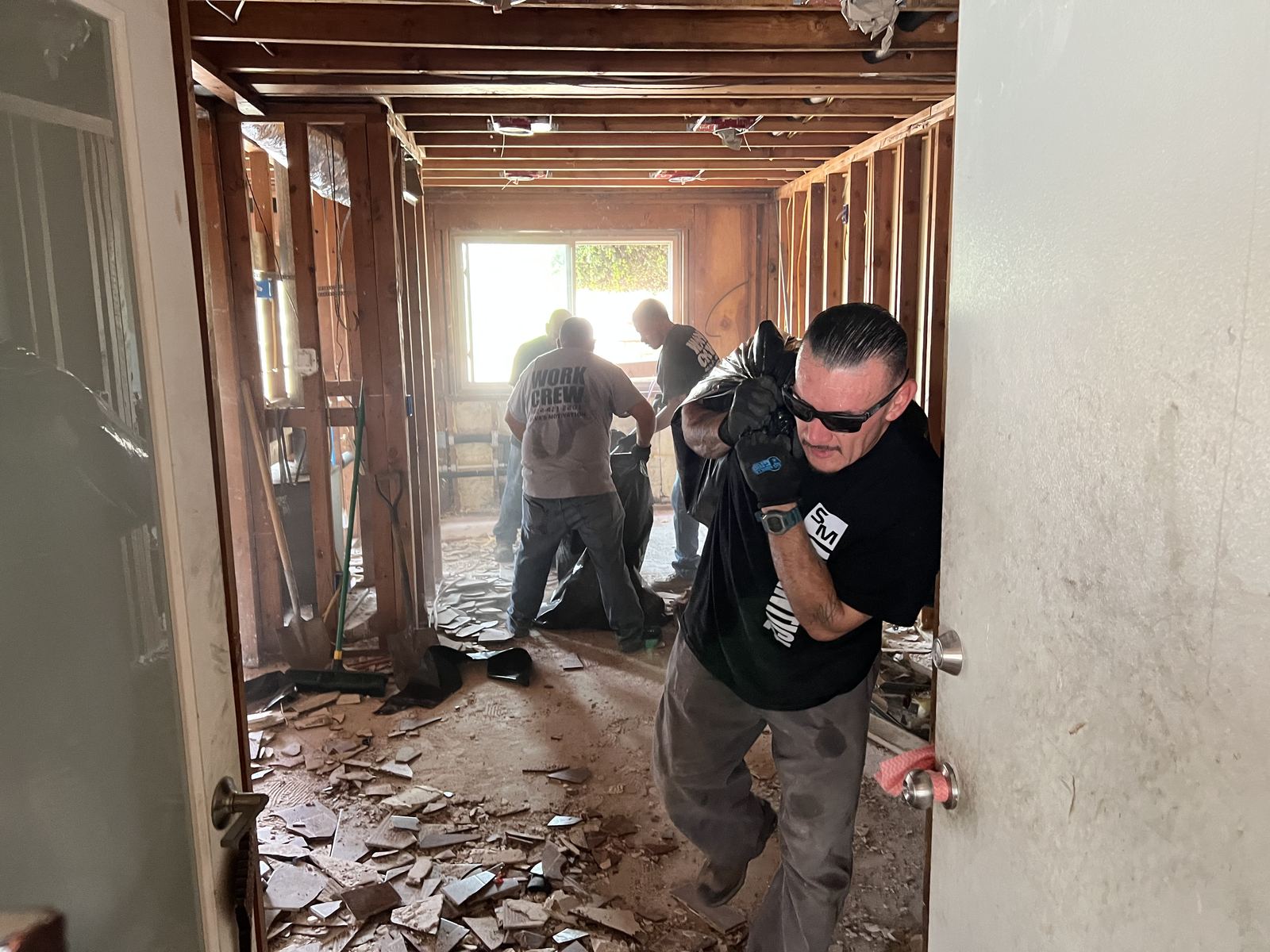 Work crew member hauling out demolition debris in bags
