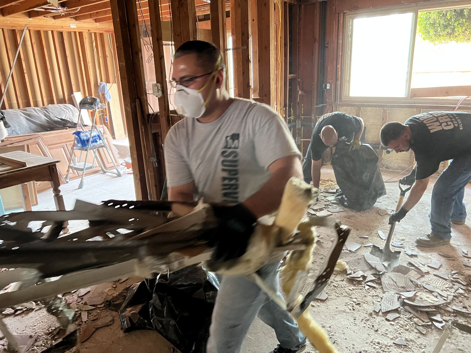 Crew member in a dust mask removing an old cabinet during renovation